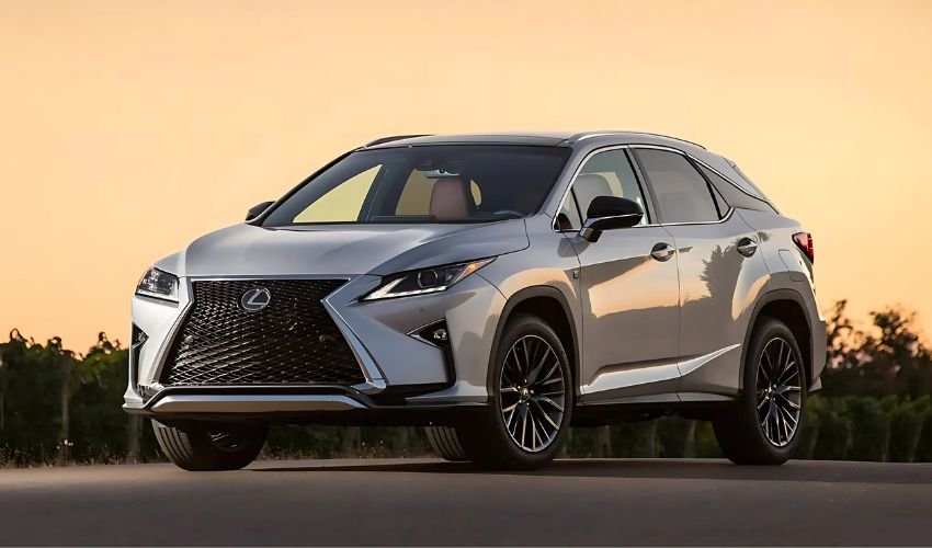 A silver Lexus RX SUV parked on a road with a vineyard and sunset in the background