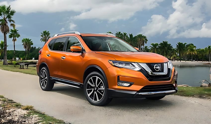 An orange Nissan Rogue driving along a scenic coastal road with palm trees.