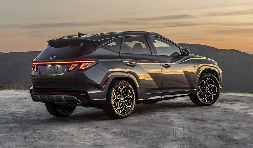 A Hyundai Tucson Hybrid SUV parked on a hilltop at sunset.