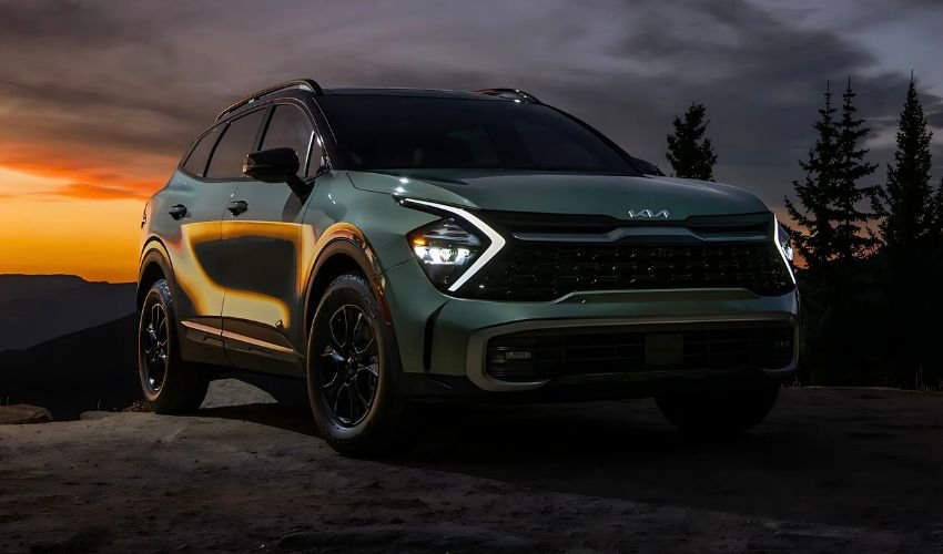 A green Kia Sportage X-Line parked on a rocky cliff at sunset