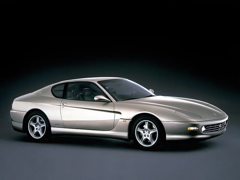 A silver Ferrari 456 GT sports car against a dark background.