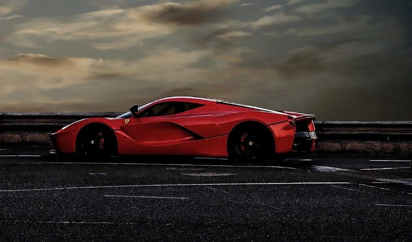  A sleek red Ferrari LaFerrari parked on a tarmac in a windy weather.