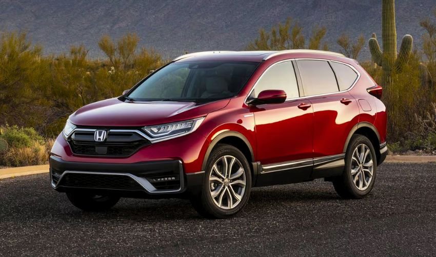 A bright red Honda CR-V parked in a desert landscape with mountains and cacti in the background