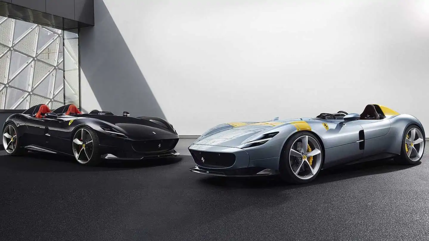 Two sleek Ferrari Monza SP1 and SP2 barchettas parked in a modern garage.