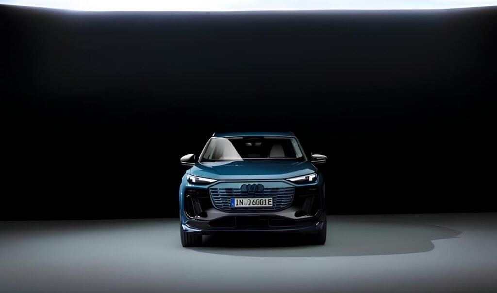 A dark blue Audi Q6 Etron SUV parked in a dark studio.