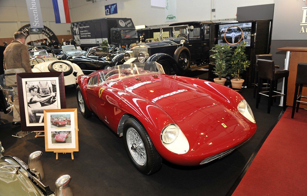 A classic car show featuring a prominent red vintage Ferrari Mondial in the foreground.