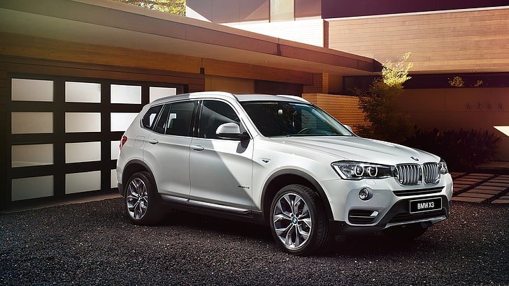 A silver 2017 BMW X3 SUV parked in front of a modern house.