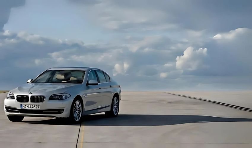 A silver BMW 5 Series sedan parked on a runway