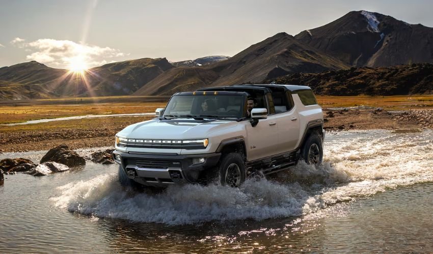 A white GMC Hummer EV driving through a shallow river