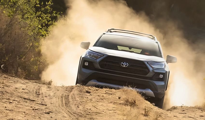 A Toyota SUV kicking up dust as it drives off-road through a rugged, forested terrain.