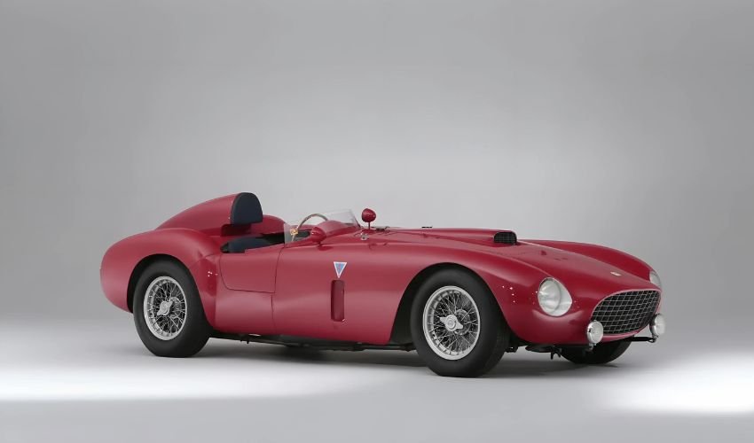 Vintage Ferrari race car parked in a gray studio setting